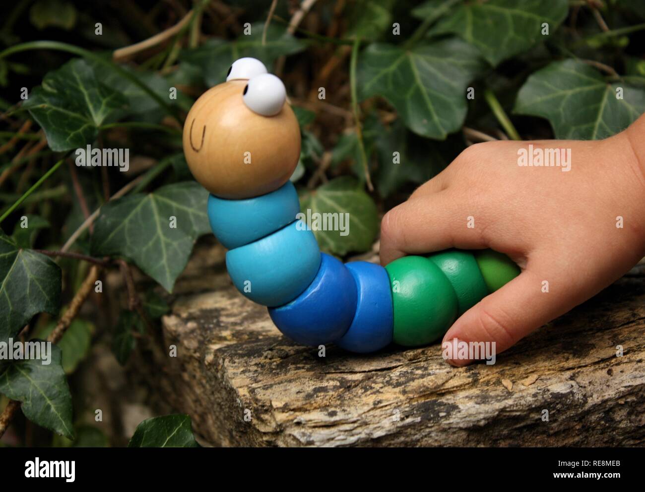 Childs hand mit einem Holz- Caterpillar Spielzeug Stockfoto