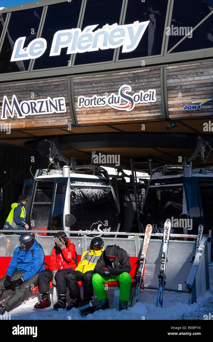 Skifahrer tragen bunte warme Kleidung sitzen auf einer Bank im Le Sonnenstühle Gondelfahrt in Morzine Haute Savoie Portes du Soleil Frankreich Stockfoto