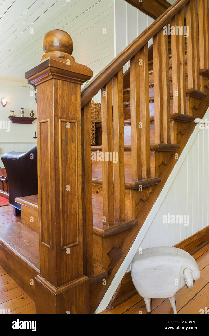 Braune Fleckenholztreppe zwischen dem Esszimmer und dem Wohnzimmer in einem alten Haus im Cottage-Stil aus den 1892 Jahren. Stockfoto