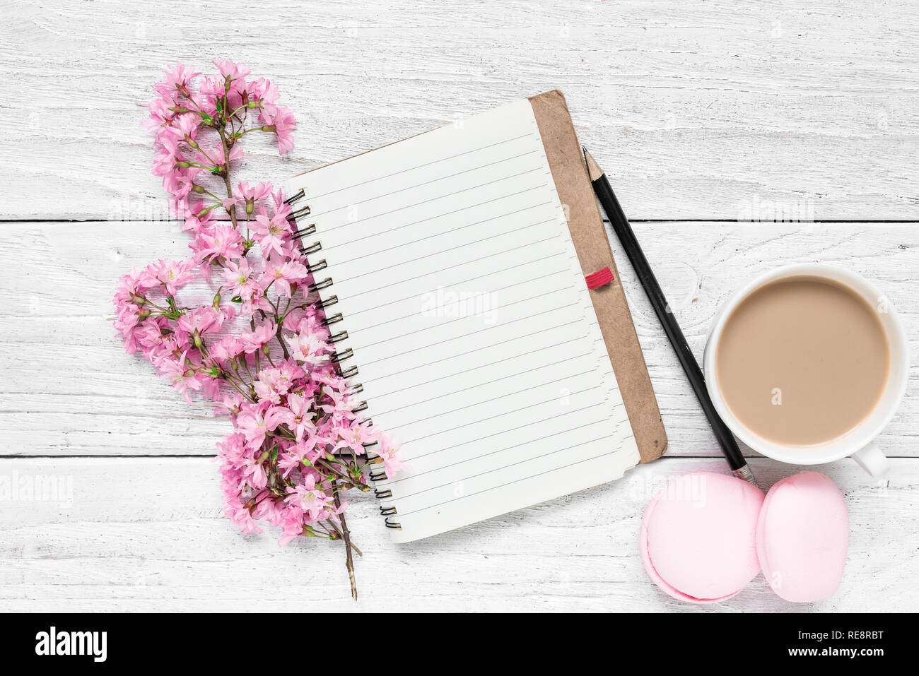 Kreative Gestaltung mit Feder cherry blühenden Blumen, leere Notepad, Makronen und Kaffee Tasse auf weißem Holz- Hintergrund. Flach. top Aussicht. Wir Stockfoto