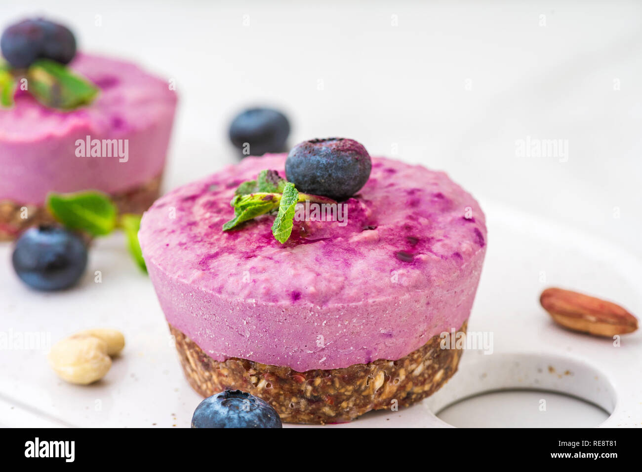 Raw Heidelbeeren und Acai veganer Käsekuchen mit frischen Beeren, Minze, Muttern. Gesunde vegane Ernährung Konzept. Nach oben Schließen Stockfoto