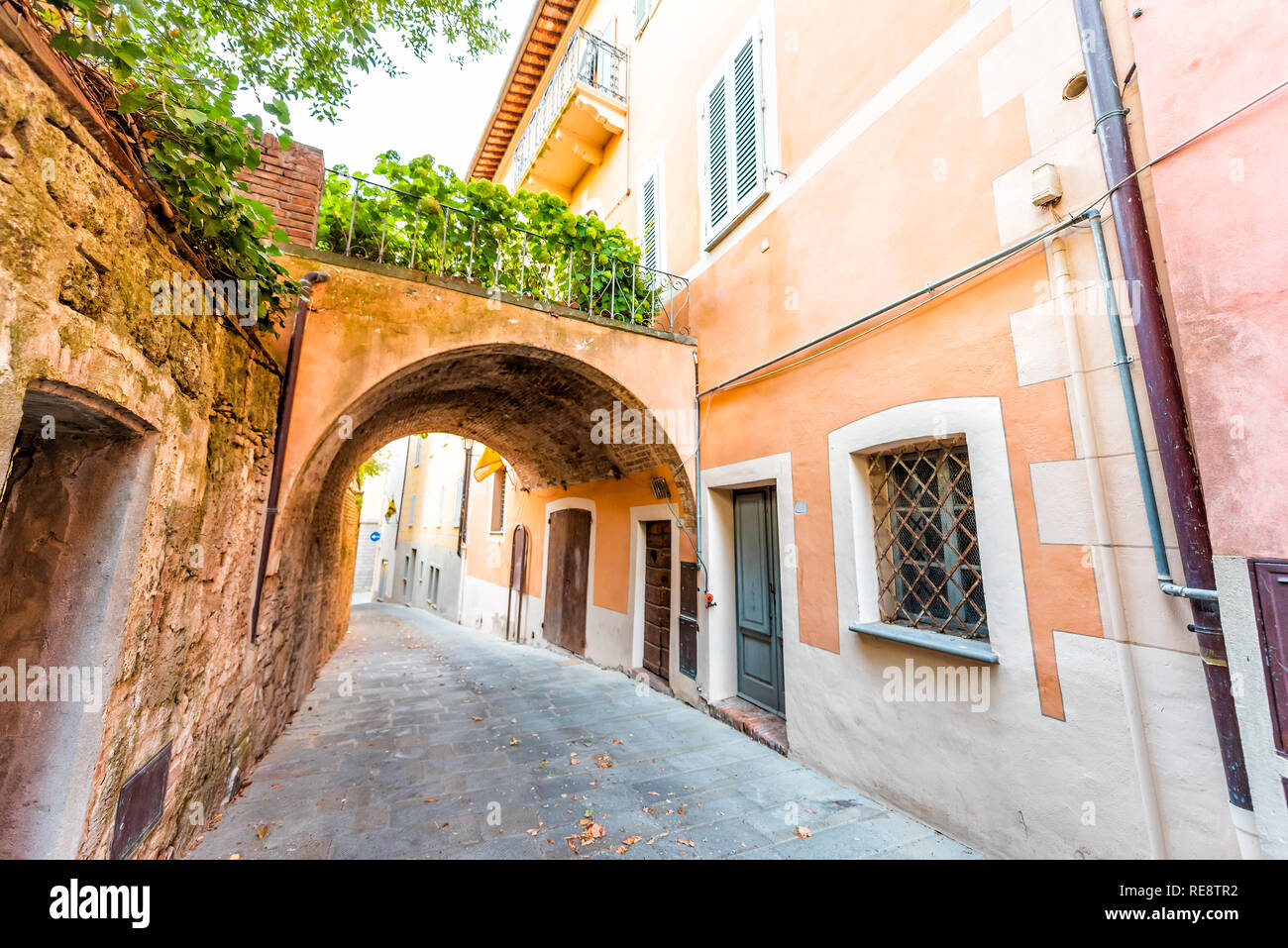 Chiusi, Italien Straße in kleinen mittelalterlichen Stadt Dorf in Umbrien während der sonnigen Tag mit niemand Orange Gelb Pink vibrant bunte Wände und Arch Stockfoto
