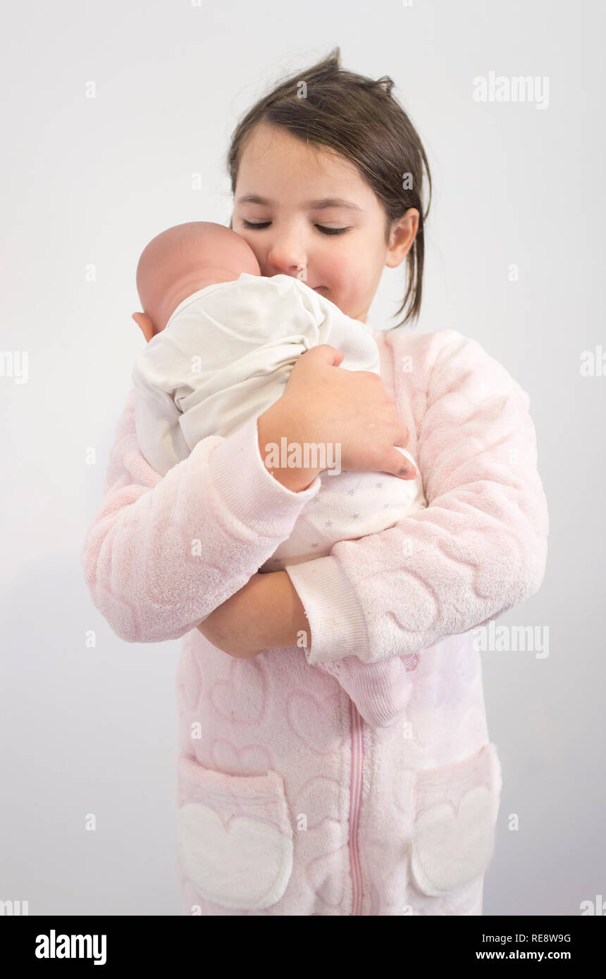 6 Jahre kleines Mädchen liebevoll hält Ihre reborn Puppe. Über weiß Isoliert Stockfoto