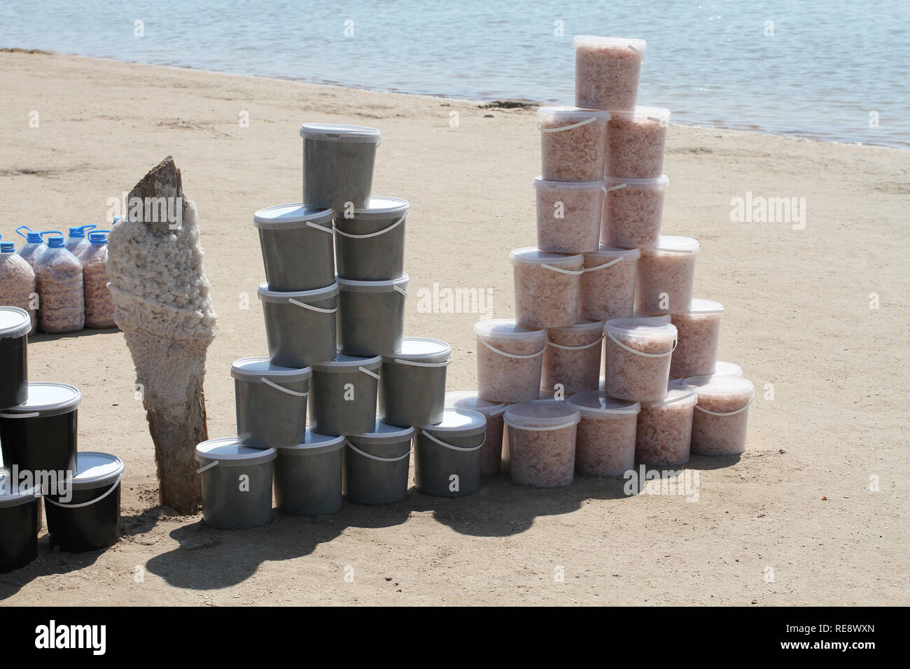 Kunststoffbehälter mit Heilschlamm und Salz und großen Kunststoff Flaschen von Salz auf der Bank von sivash See Stockfoto