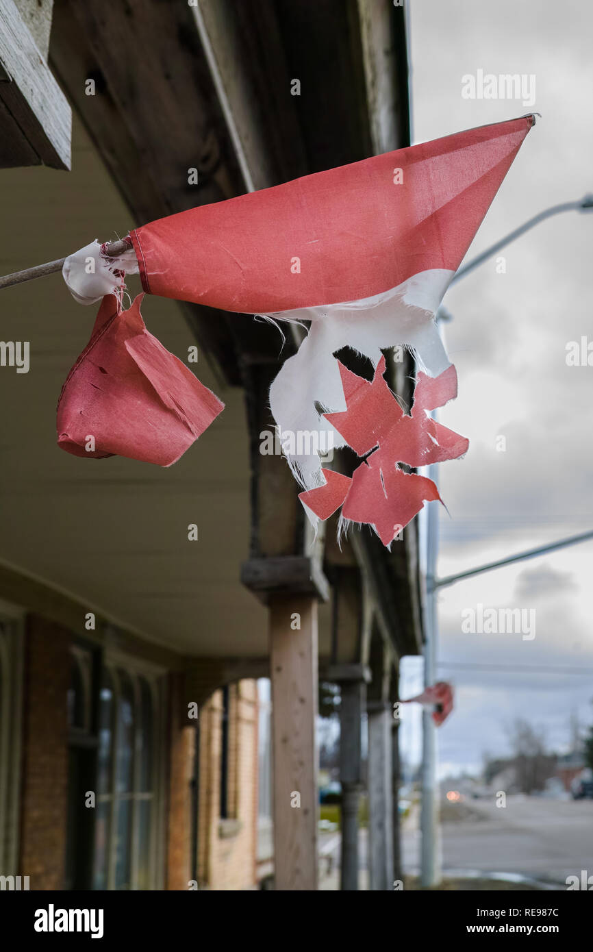 Ein abgenutzter und zerrissen kleinen Kanadischen Flagge, Leider hängen an der Seite eines historischen Gebäudes. Stockfoto