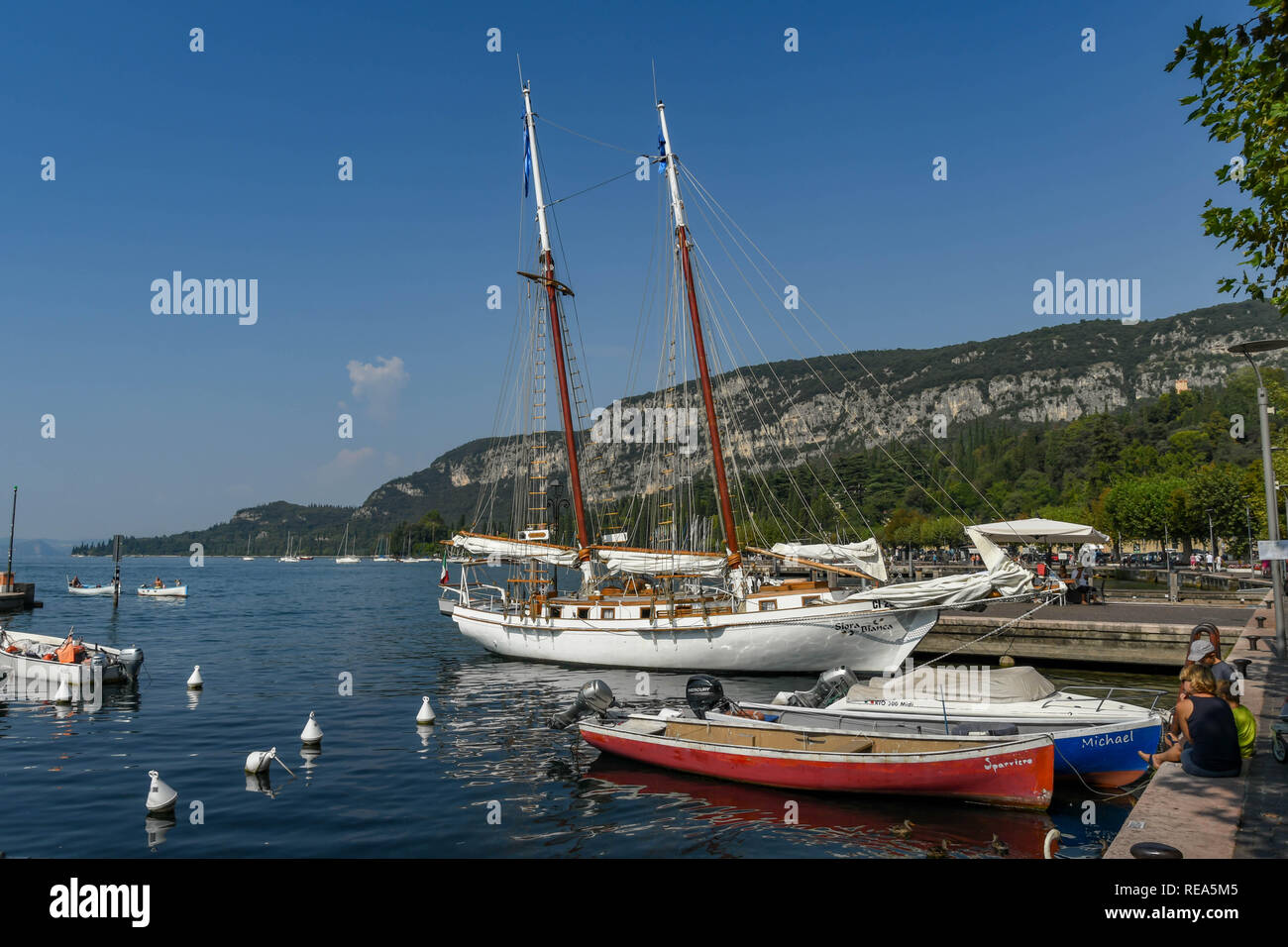 Gardasee, Italien - September 2018: Kleine Boote und ein Segelboot im Hafen in der Stadt Garda am Gardasee günstig. Stockfoto