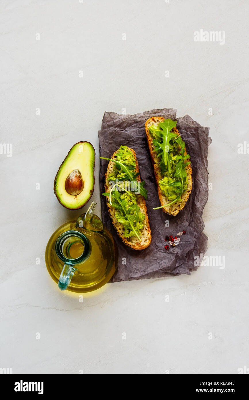 Frische Toasts mit Avocado und Rucola flach. Gute Fette raw Gesunde Ernährung Konzept. Stockfoto