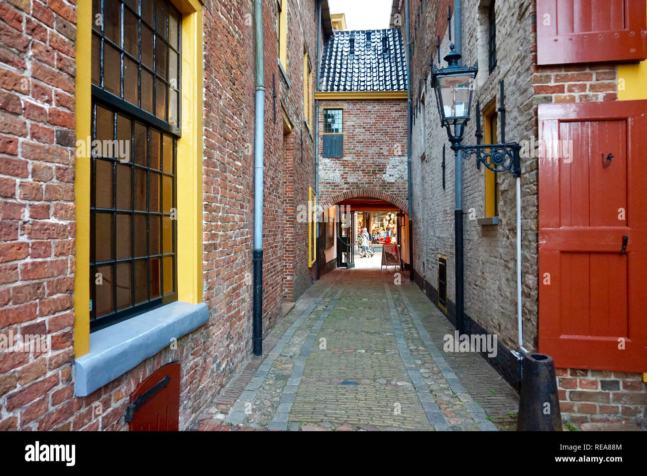 Groningen, Niederlande: restaurierte mittelalterliche Gebäude in Europa, mit hellen roten und gelben trimmen. Alten Ziegel Straße Gasse mit Laterne und Bügeleisen frame Stockfoto