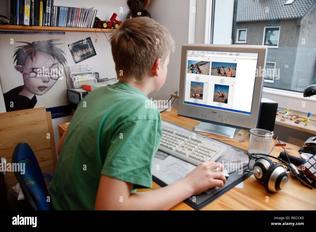 Junge, 13, mit seinem Computer zu Hause arbeiten, anzeigen Urlaub Fotos in einem Bildbearbeitungsprogramm Stockfoto