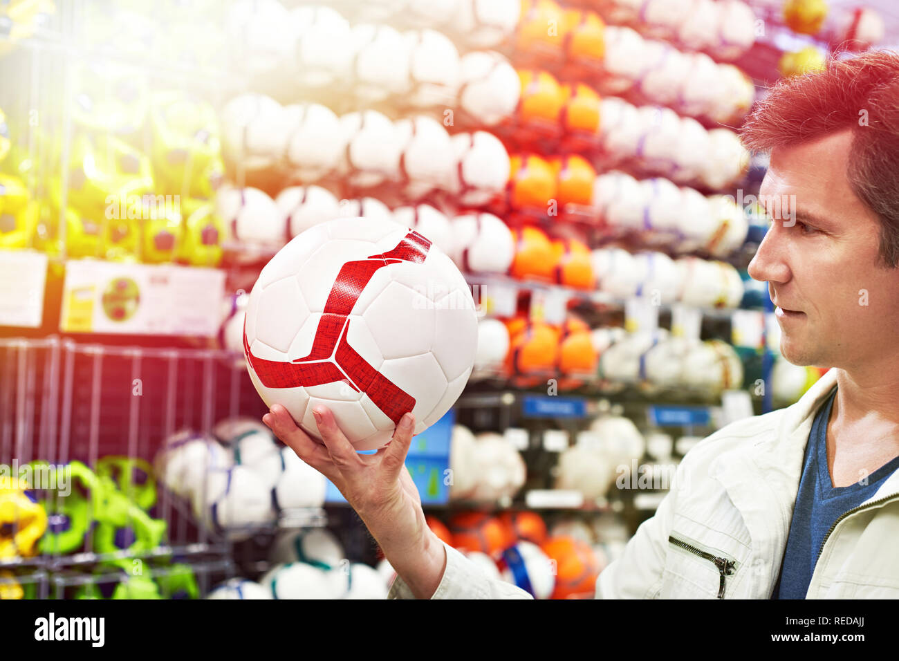 Mann mit einem Fußball im Sportgeschäft Stockfoto