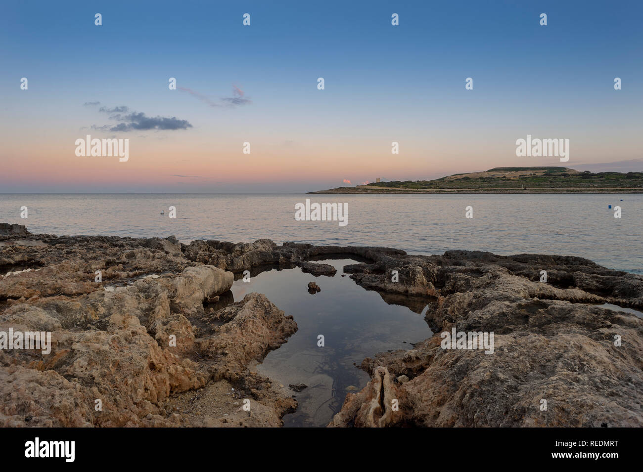 Blick auf Salina Bay, Malta in der Dämmerung mit Rock Pools im Vordergrund. Stockfoto