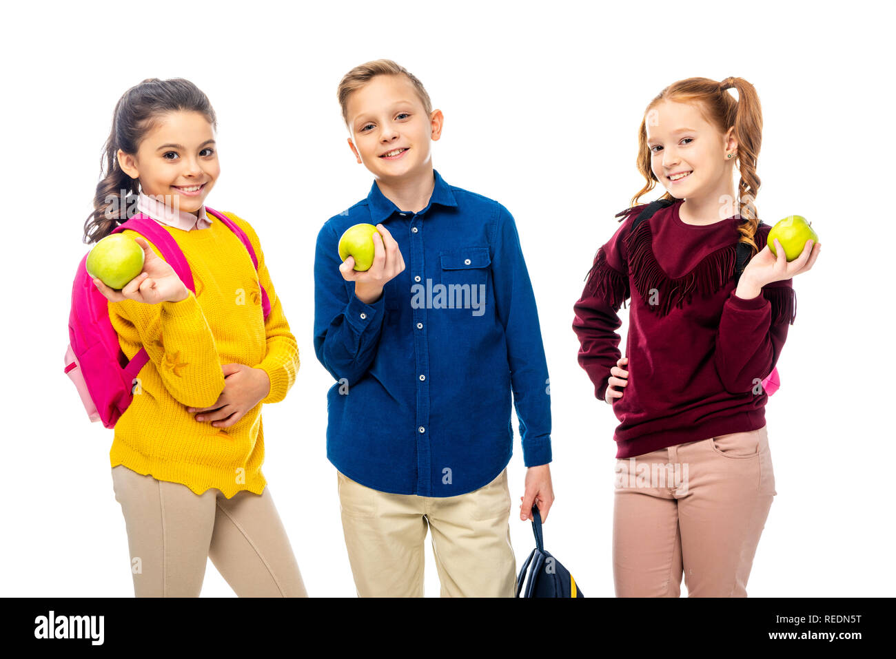 Cute Schulkinder mit Rucksäcken holding Äpfel und Kamera isoliert auf weißem Stockfoto