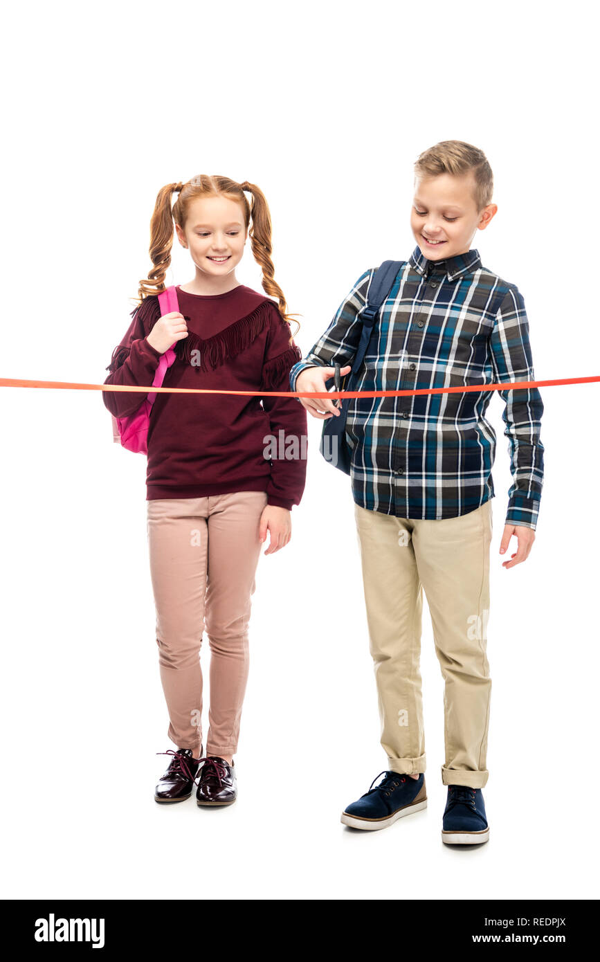 Lächelnd Schulkinder mit Rucksäcken schneiden red ribbon isoliert auf weißem Stockfoto