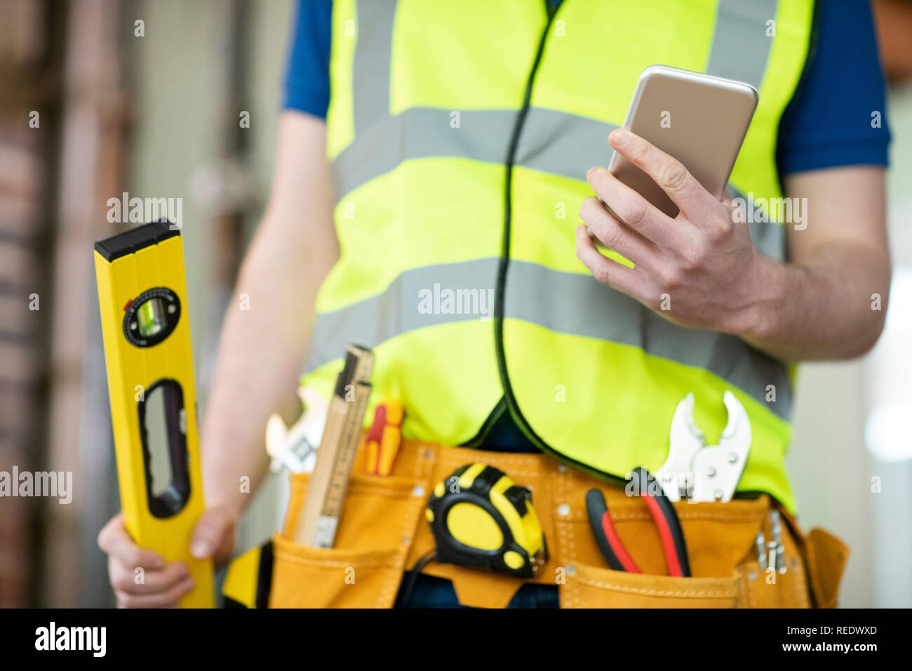 Detail der Bauarbeiter auf der Baustelle tragen Werkzeuggürtel mit Handy Stockfoto