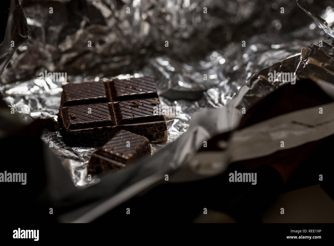 Makro Foto von dunkler Schokolade Stücke in Folienverpackung. Stockfoto