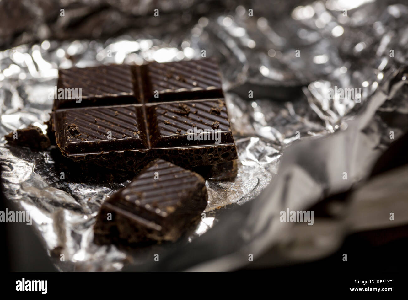 Makro Foto von dunkler Schokolade Stücke in Folienverpackung. Stockfoto