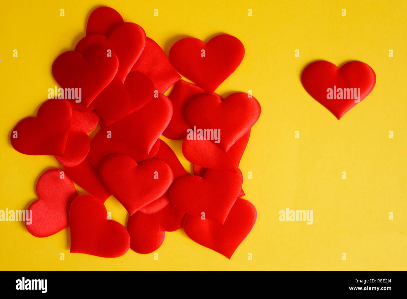 Eine Menge Satin rot Herzen auf einem gelben Oberfläche. St Valentines Tag. Herzlichen Glückwunsch zum Valentines Tag. Liebe und Einsamkeit. Stockfoto