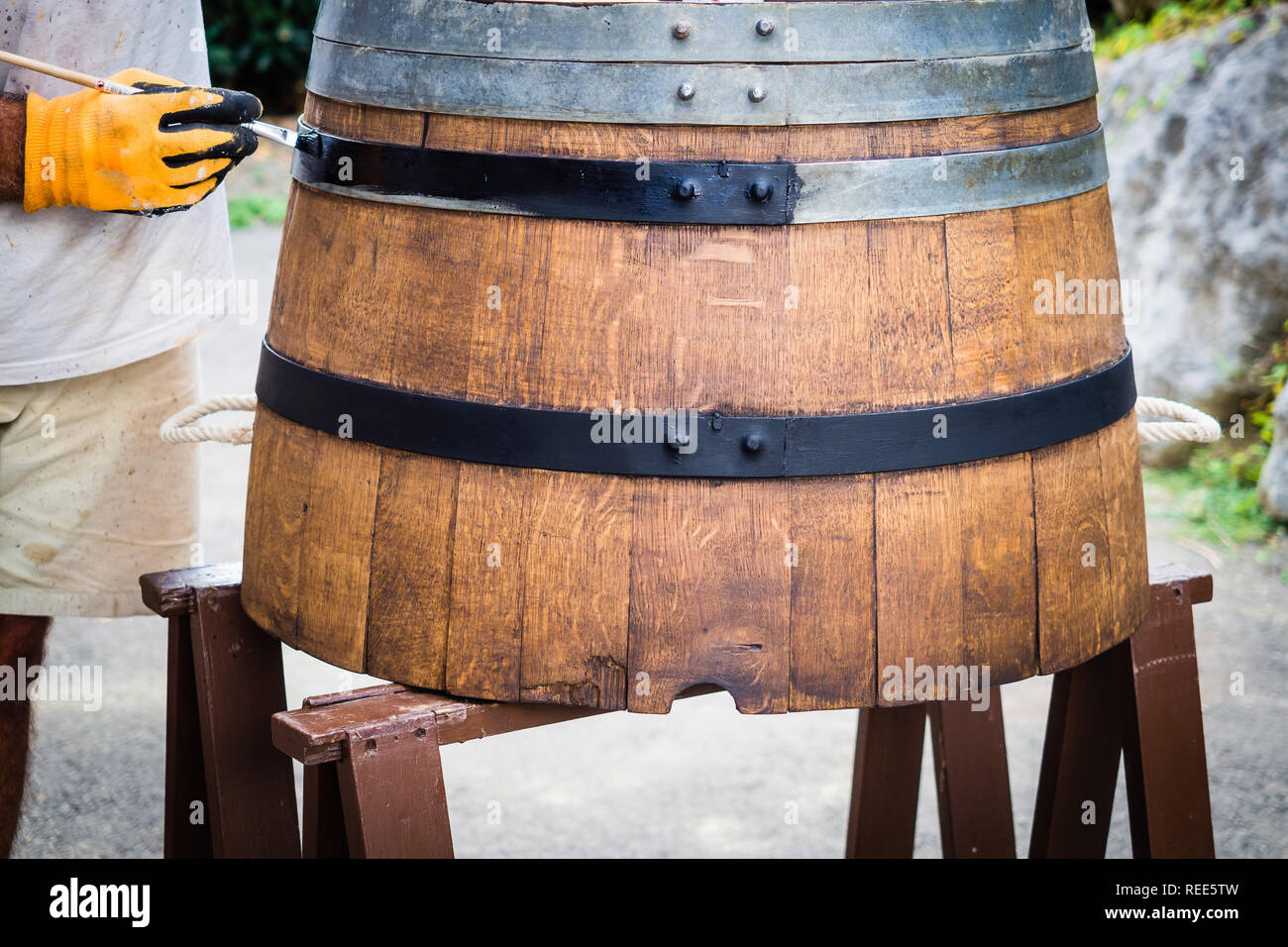 Barrel Restaurierung, ein Mann, ein alter Wein Faß. Die Hälfte barrel für Pflanzen und Garten. Schwarzen Lackierung Stockfoto