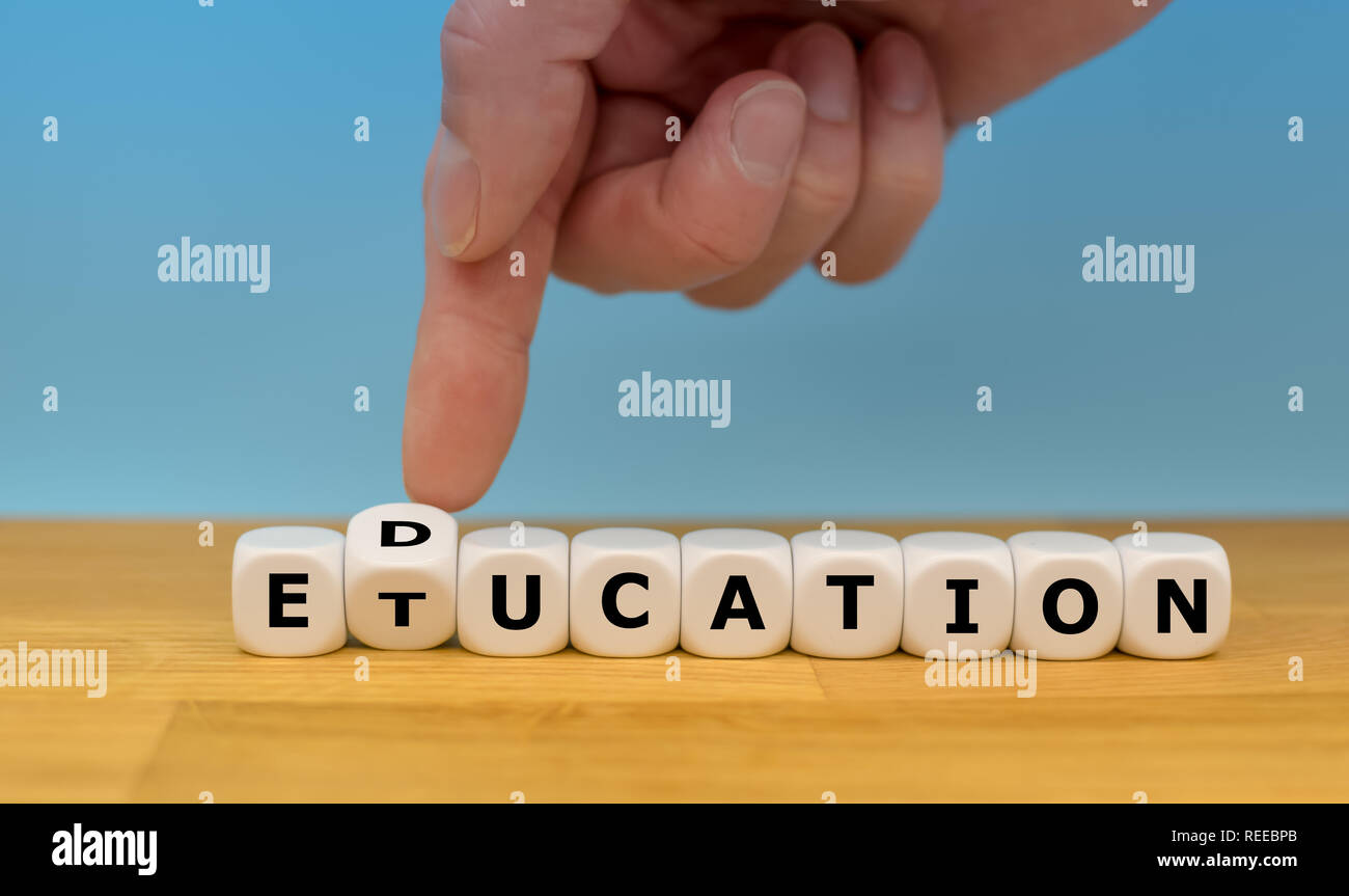 Bildung ist dringend erforderlich. Hand einen Würfel und symbolisch korrigiert das falsch geschriebene Wort "Etucation' zu 'Bildung' Stockfoto