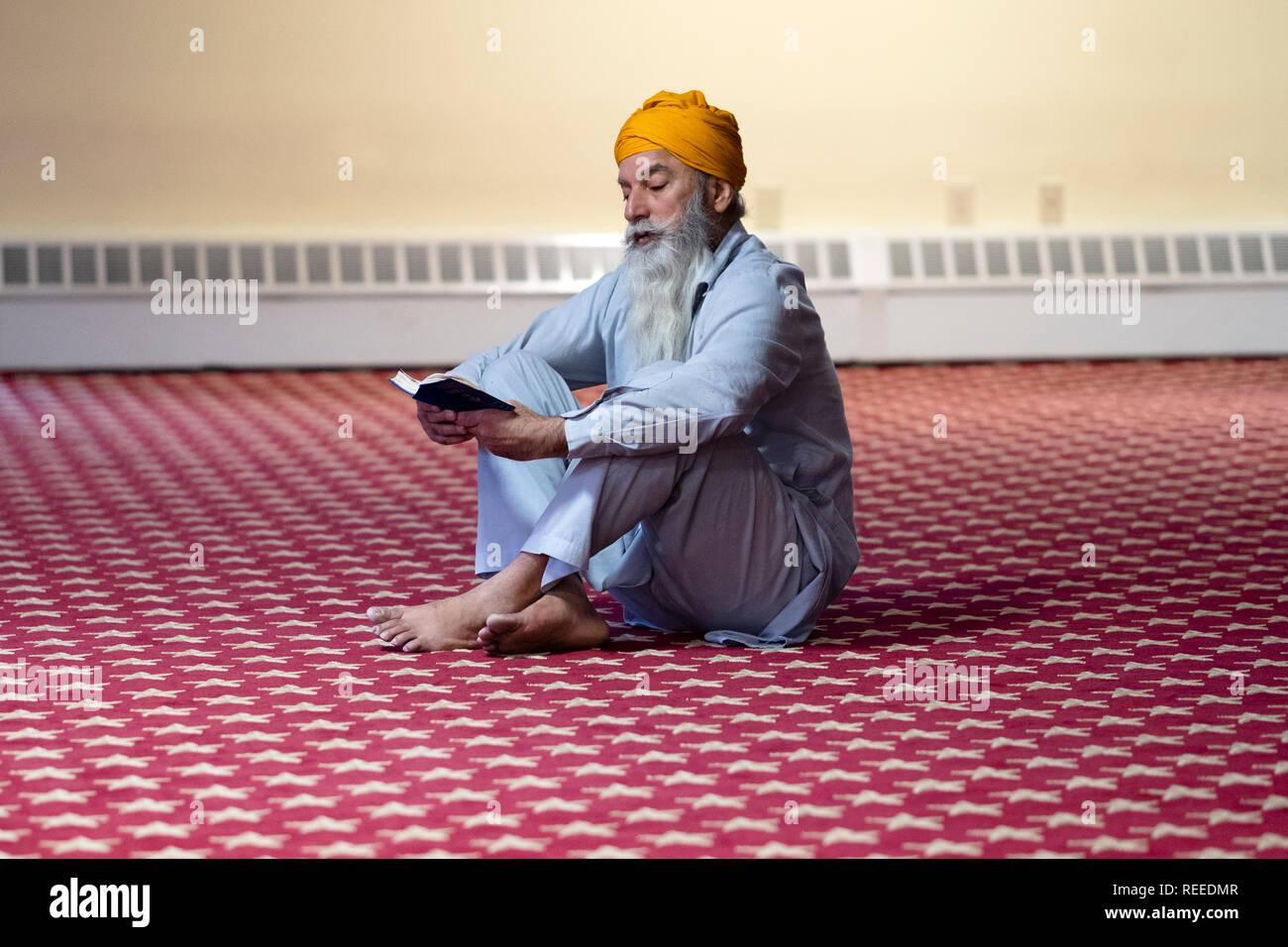Ein frommer Sikh mann Lesung sein Gebet Buch an einem Tempel in Richmond Hill, Queens, New York City. Stockfoto