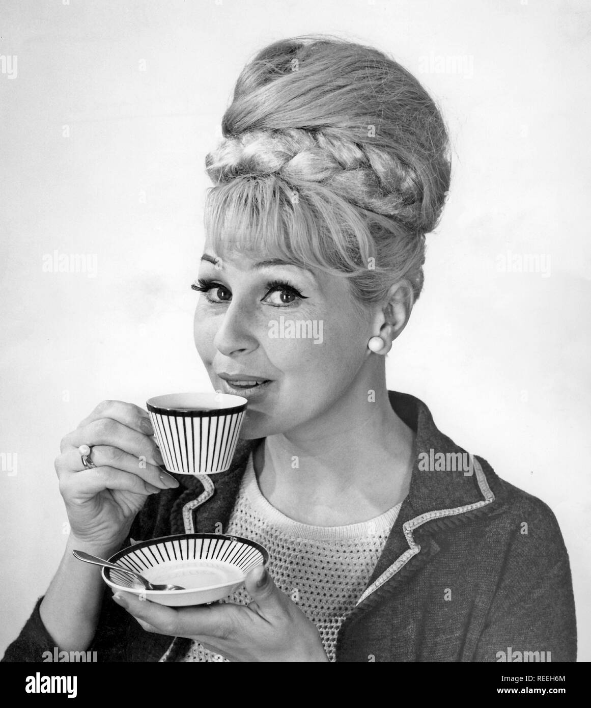 Kaffee in den 1960er Jahren. Eine Frau trinkt Kaffee aus einer Kaffeetasse mit einem 1960er Streifenmuster. Sie hat ihr Haar in den typischen Bienenstock Frisur, in denen lange Haare auf dem Kopf aufgetürmt ist und eine gewisse Ähnlichkeit mit der Form eines traditionellen Bienenstock. Schweden 1962 Stockfoto
