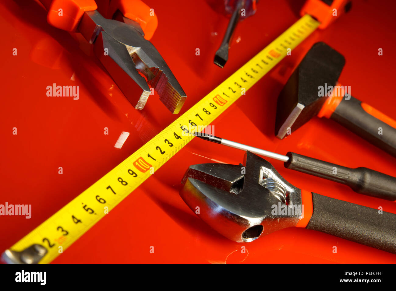 Maßband, Hammer, Schraubendreher, Zangen, und verstellbarer Schraubenschlüssel auf einem roten polierte Oberfläche. Werkzeuge für die Mechaniker. Stockfoto