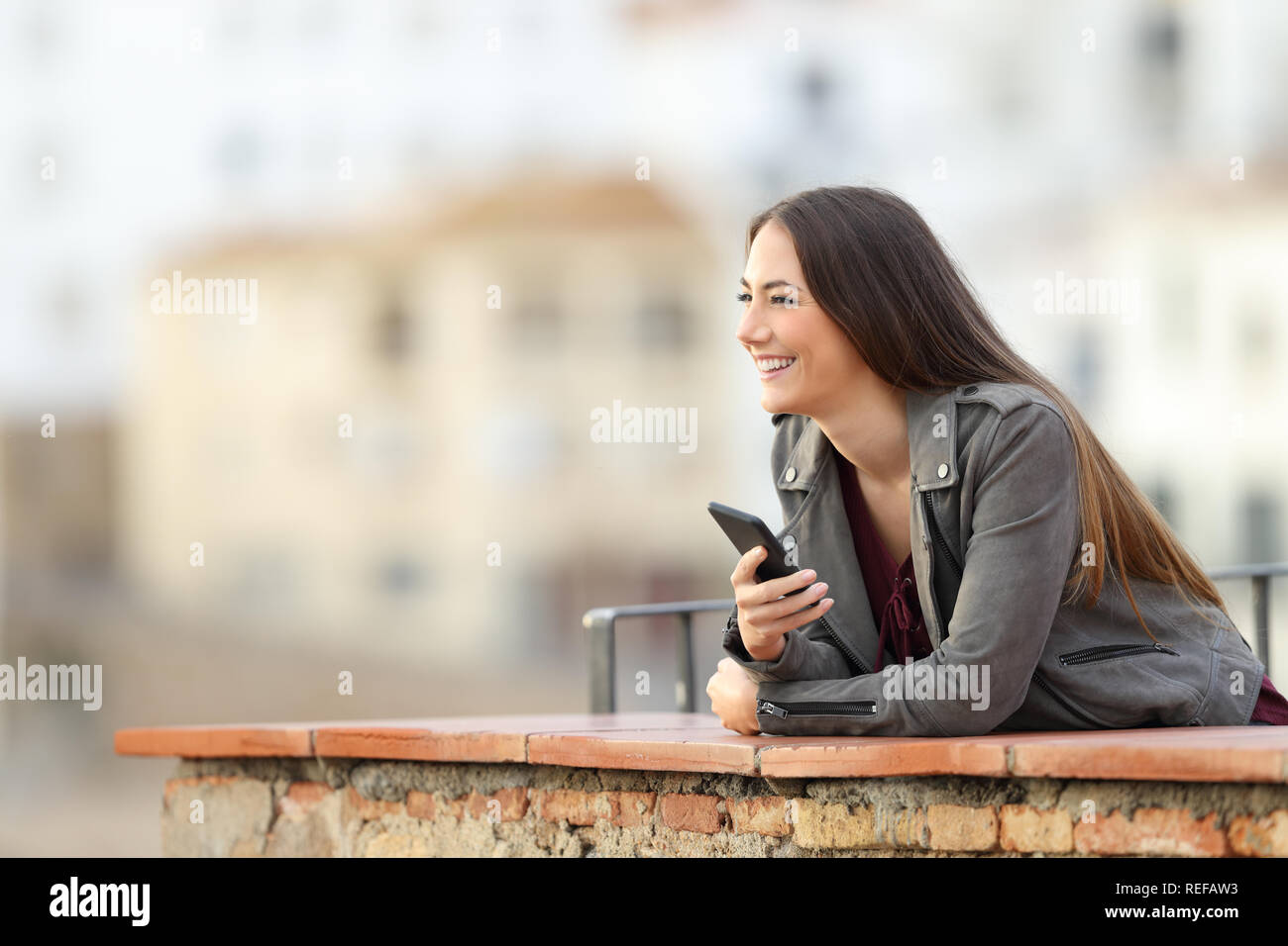 Happy woman holding Smart Phone, die Landschaft draußen in einer Stadt Stadtrand Stockfoto