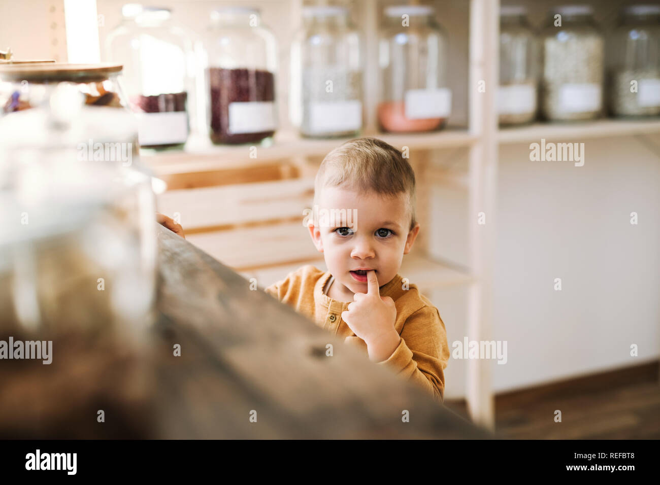 Eine kleine Kleinkind Junge an der Theke in null Abfall Shop. Stockfoto