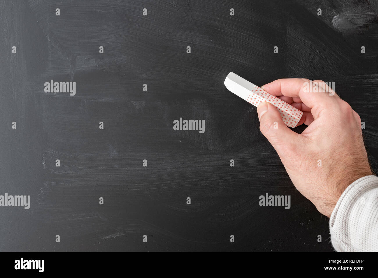 Hand mit Stick von Kreide gegen Schiefertafel Stockfoto