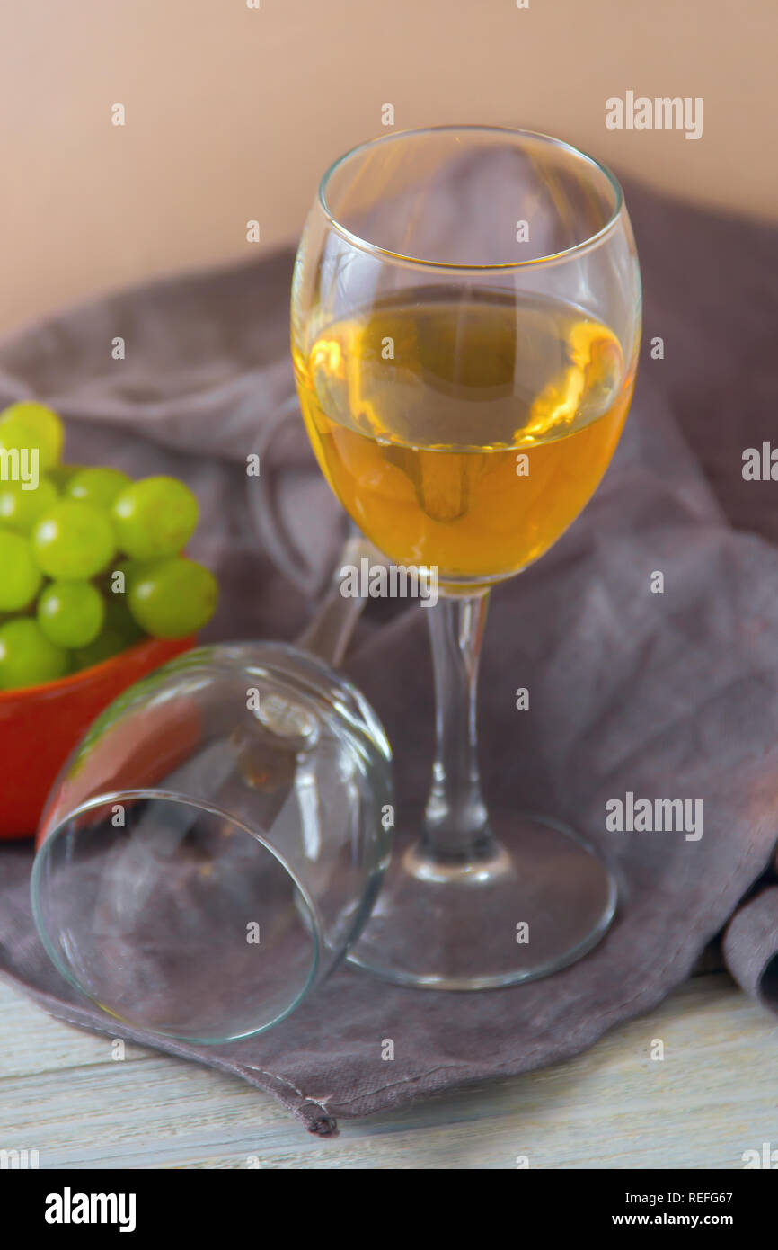 Zwei Weingläser, grüne Trauben auf dem Teller auf dem Tisch. Stockfoto