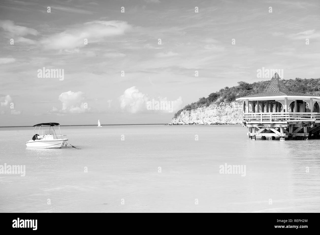 Meer Strand mit Boot und Holz- Schutz auf türkisfarbenes Wasser in St. Johns, Antigua am blauen Himmel Hintergrund. Sommer Urlaub auf Karibik. Abenteuer, Reisen, Fernweh Konzept Stockfoto