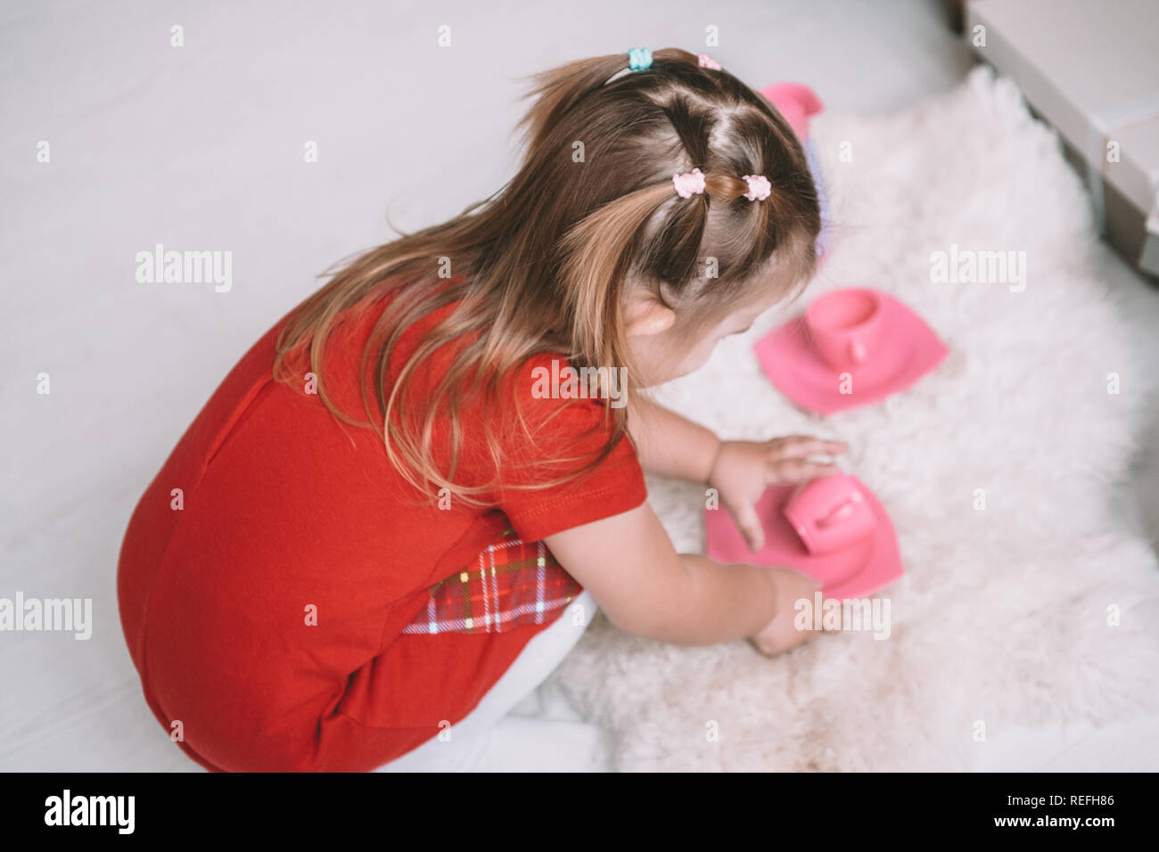 Kleine Mädchen spielen Spielzeug baby Gerichte zu Hause Stockfoto