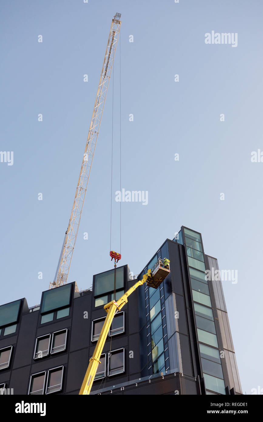 Arbeiter Bedienen von Maschinen an der Spitze eines hohen Gebäudes Stockfoto