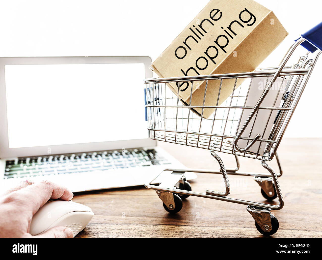 Online shopping Konzept mit Miniatur Warenkorb und Laptop am Tisch Stockfoto