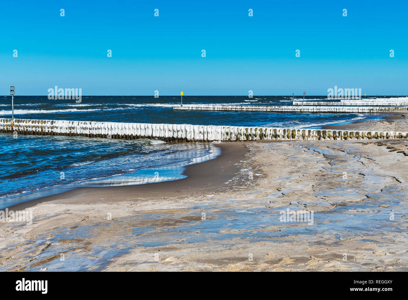 Strand der Ostsee in Kolberg im Winter. Eis bedeckt Buhnen sind im Wasser, Kolberg, Westpommern, Polen, Europa Stockfoto
