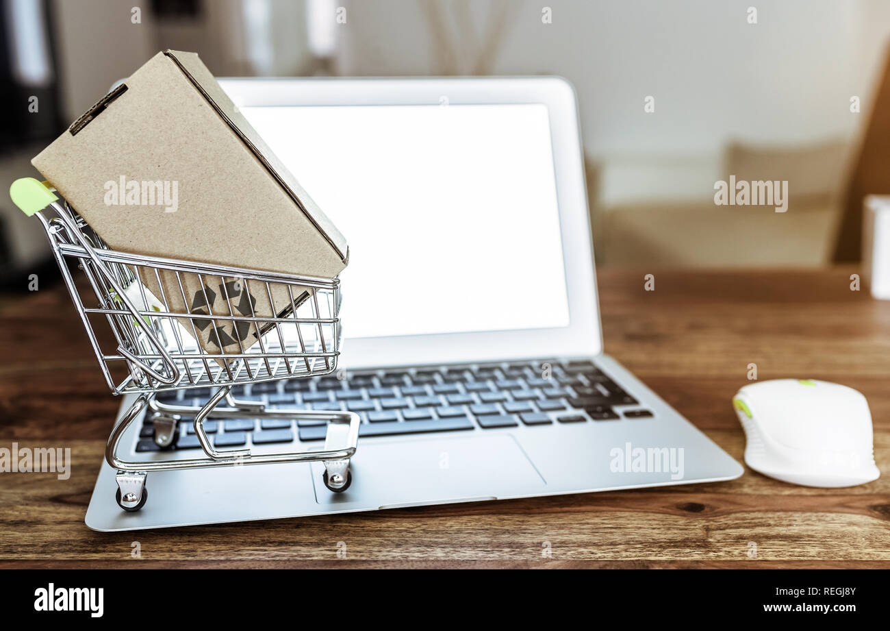 Online shopping Konzept mit Miniatur Warenkorb und Laptop am Tisch Stockfoto