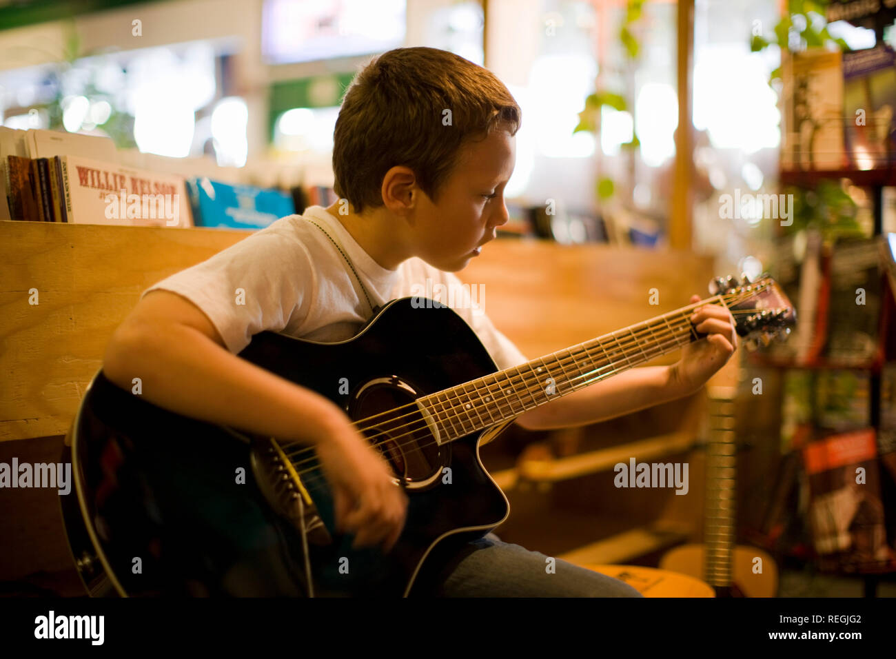 Junge strumming eine akustische Gitarre im Music Shop. Stockfoto
