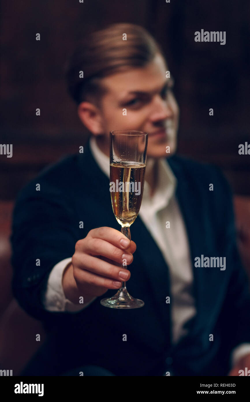 Sehr schöner Mann im Anzug hebt das Glas Champagner Stockfoto