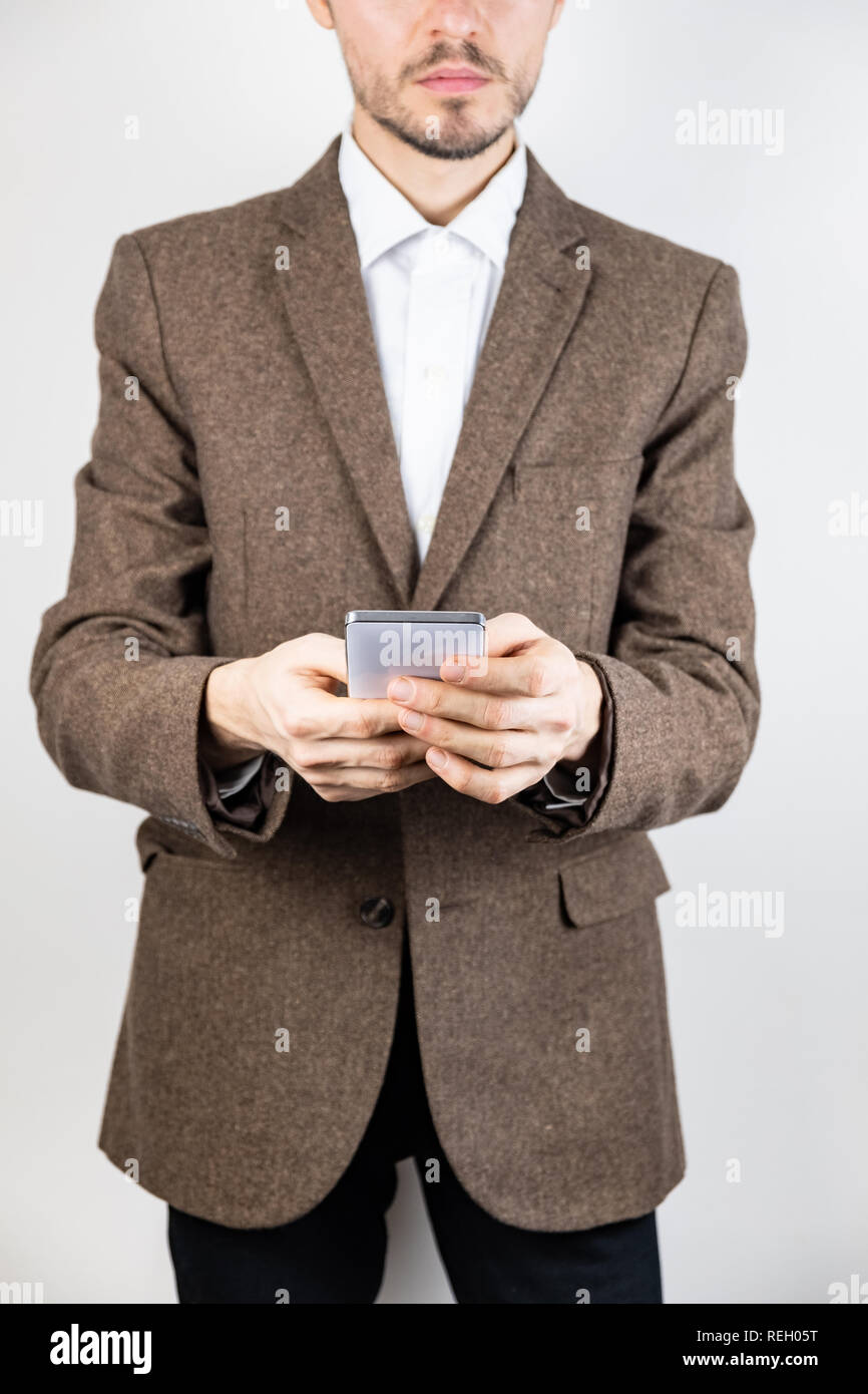 Mann in Tweed Jacke mit einem Mobiltelefon. Männliche Person im Geschäft Kleidung verwendet die Technologie, detaillierte Ansicht im weißen Hintergrund Stockfoto