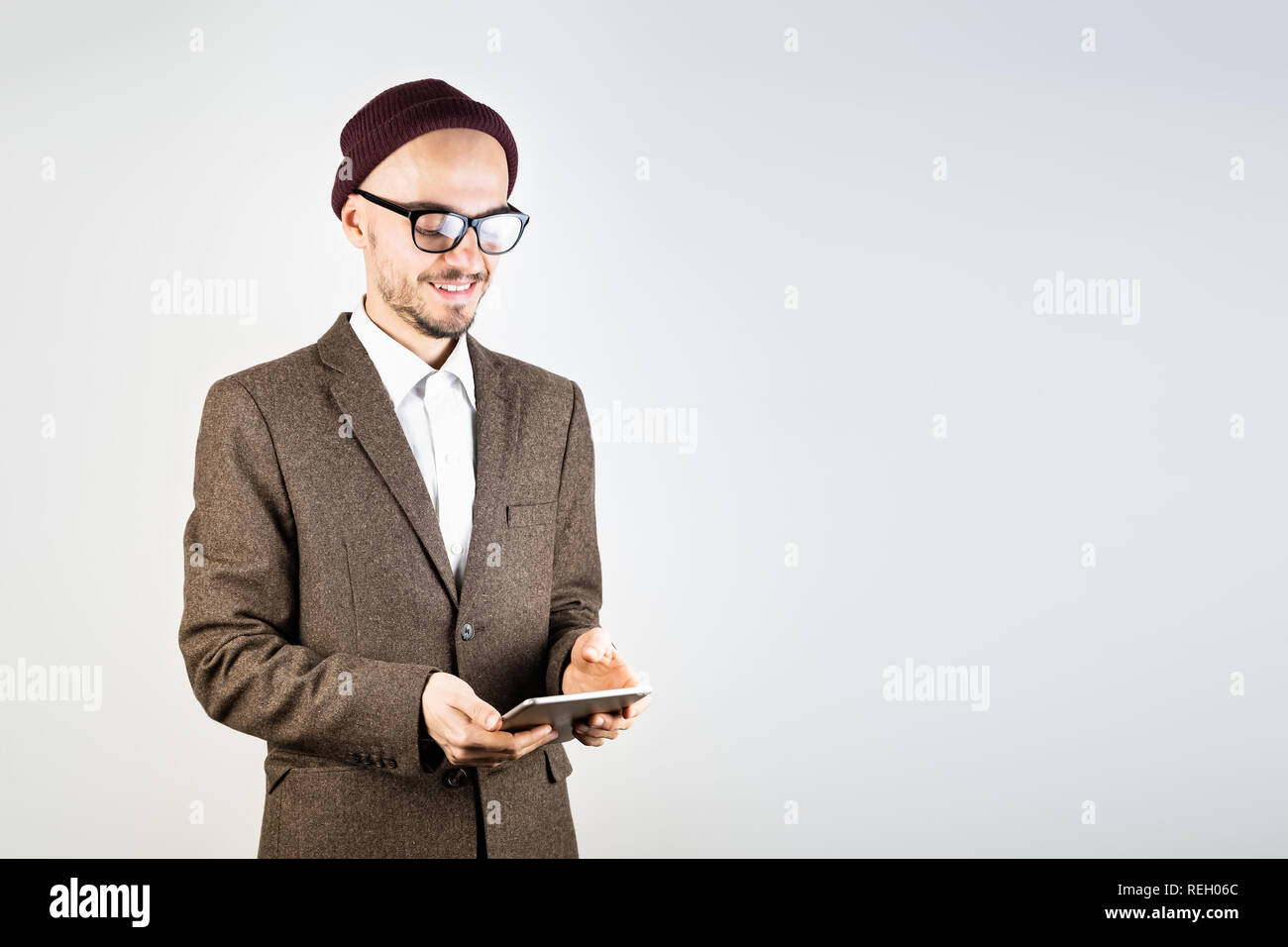 Lächelnd Mann in Tweed Jacket mit einem Tablet-PC. Männliche Person in Hipster style Kleidung verwendet die Technologie, Studio shot auf weißem Hintergrund Stockfoto