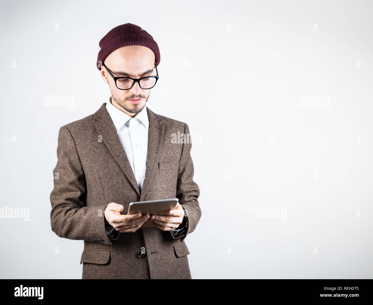 Ernster Mann in Tweed Jacket mit einem Tablet-PC. Männliche Person in Hipster style Kleidung verwendet die Technologie, Studio shot auf weißem Hintergrund Stockfoto