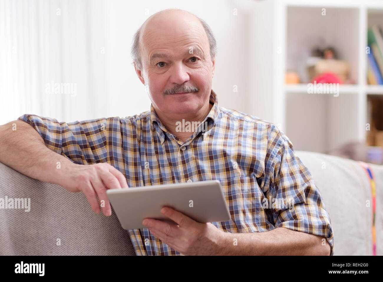 Ältere Menschen mit Tablette zu Hause sitzen. Stockfoto