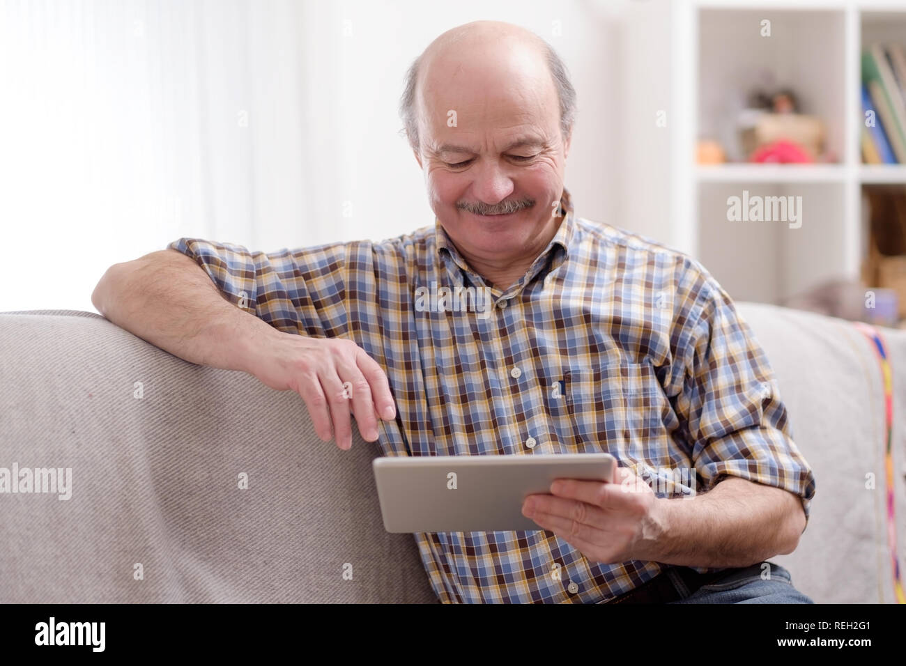 Ältere Menschen mit Tablette zu Hause sitzen. Stockfoto