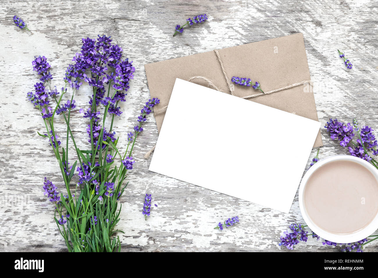 Leere weiße Grußkarte mit Lavendel Blumen Blumenstrauß über weiße Holztisch mit Tasse Cappuccino. top anzeigen. Mock up. hochzeit einladung Stockfoto