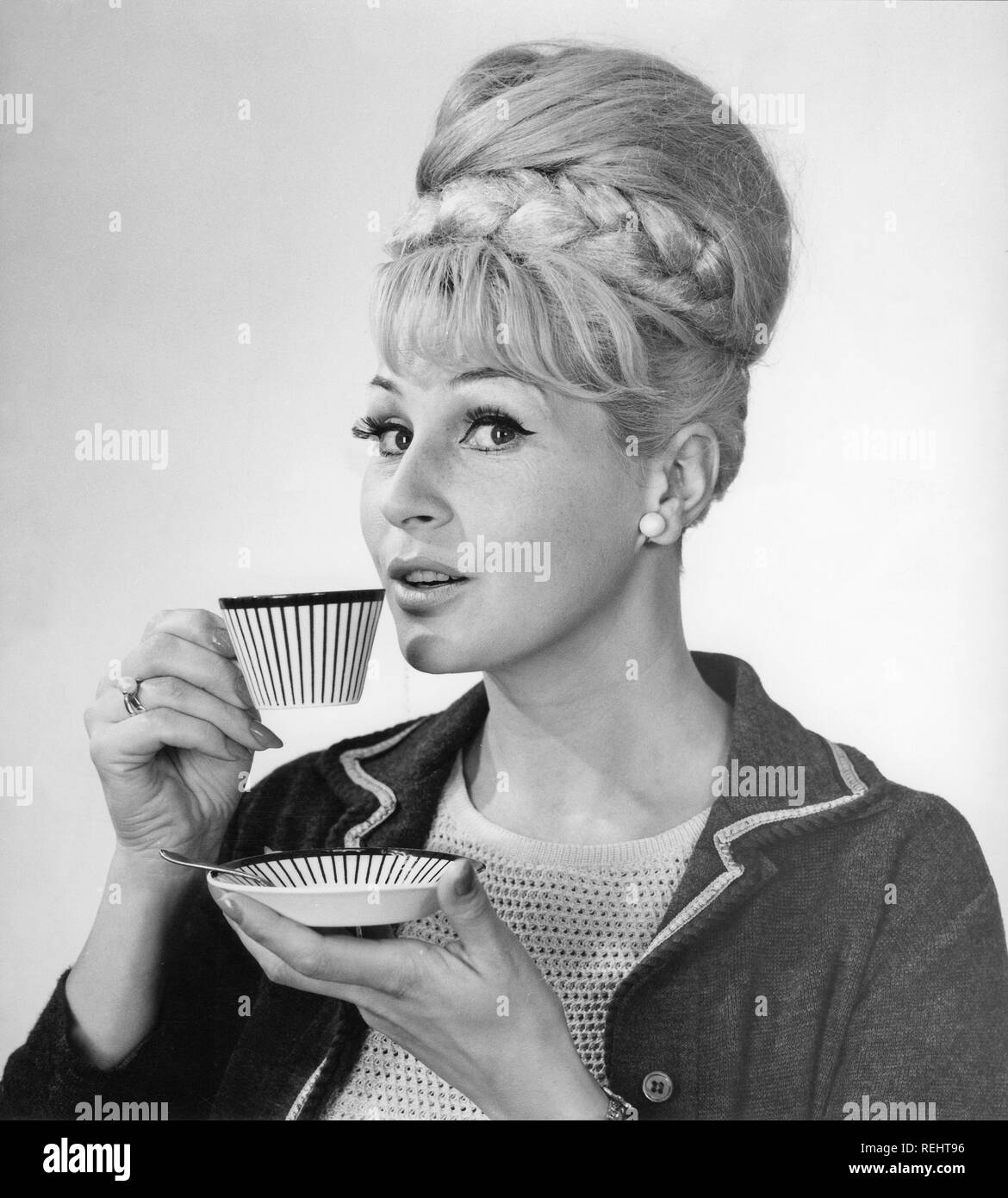 Kaffee in den 1960er Jahren. Eine Frau trinkt Kaffee aus einer Kaffeetasse mit einem 1960er Streifenmuster. Sie hat ihr Haar in den typischen Bienenstock Frisur, in denen lange Haare auf dem Kopf aufgetürmt ist und eine gewisse Ähnlichkeit mit der Form eines traditionellen Bienenstock. Schweden 1962 Stockfoto