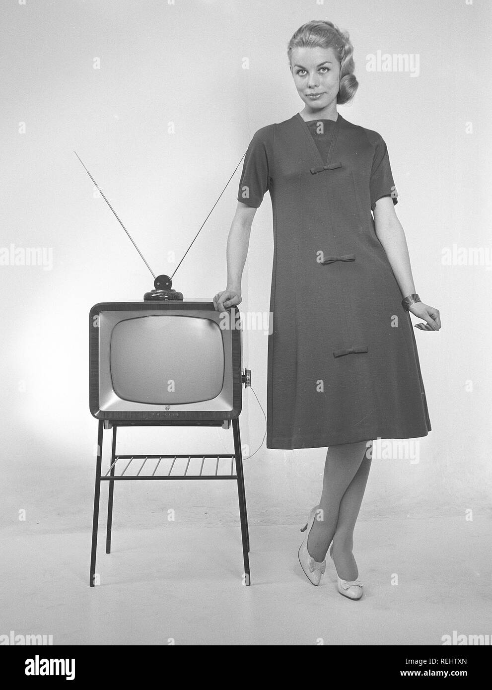 Fernsehen in den 1950er Jahren. Eine junge Frau steht in einer typischen  50er Kleid neben einem Fernseher mit einer Tabelle Antenne oben auf er Satz  gekleidet. 1952 1,4 Millionen Haushalte in Großbritannien