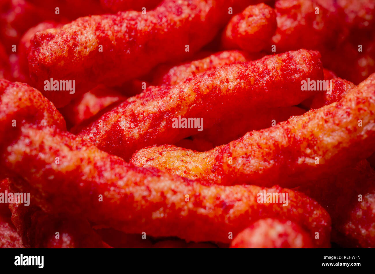 Eine enge Sicht der Flamin' Hot Cheetos enthüllt die Spicy Chili Käse Pulver Gewürz, dass Coats die aufgeblasen Maismehl Snack. Stockfoto