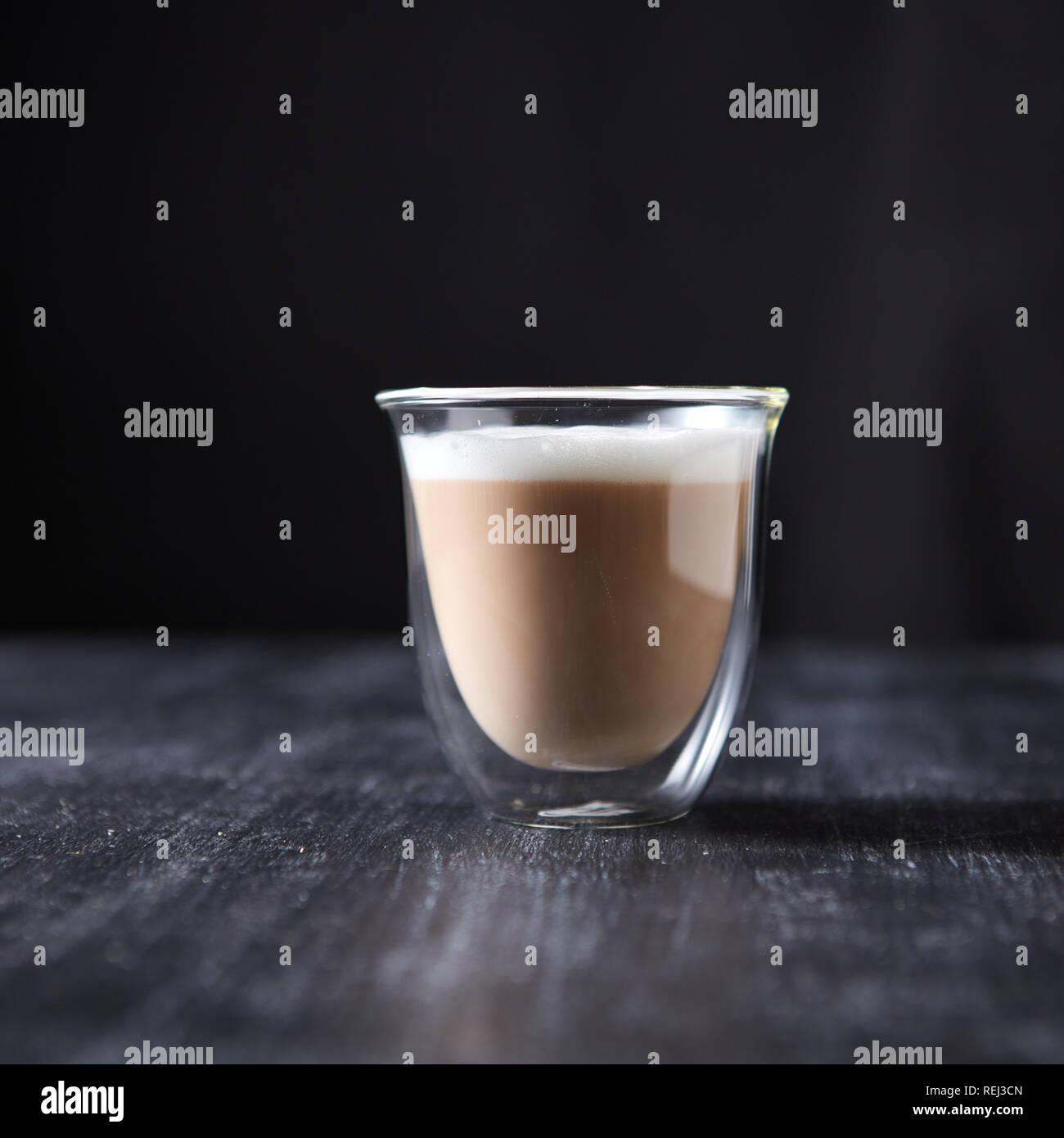 Frisch Cappuccino mit Schaumstoff in ein Glas Schale auf einem schwarzen Holztisch rund um einen dunklen Hintergrund mit Kopie Raum gebraut. Stockfoto