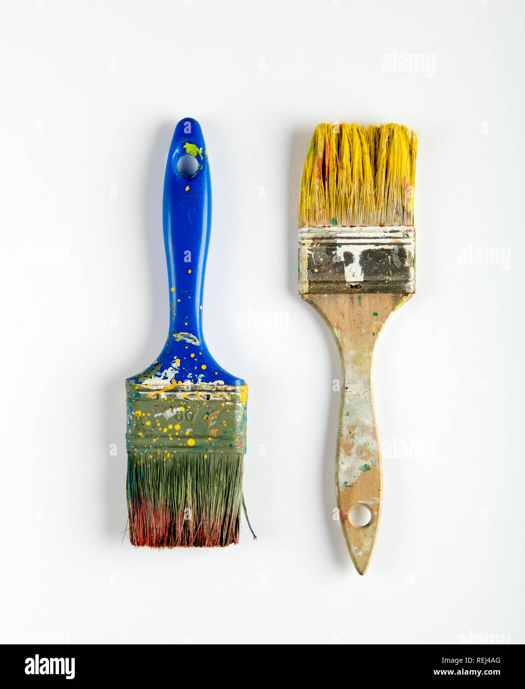 Zwei alte verschmutzte Holz- Pinsel mit gelben und braunen Flecken auf weißem Lack in einem DIY, Renovierungen, Innenausbau, oder Wartung Konzept Stockfoto