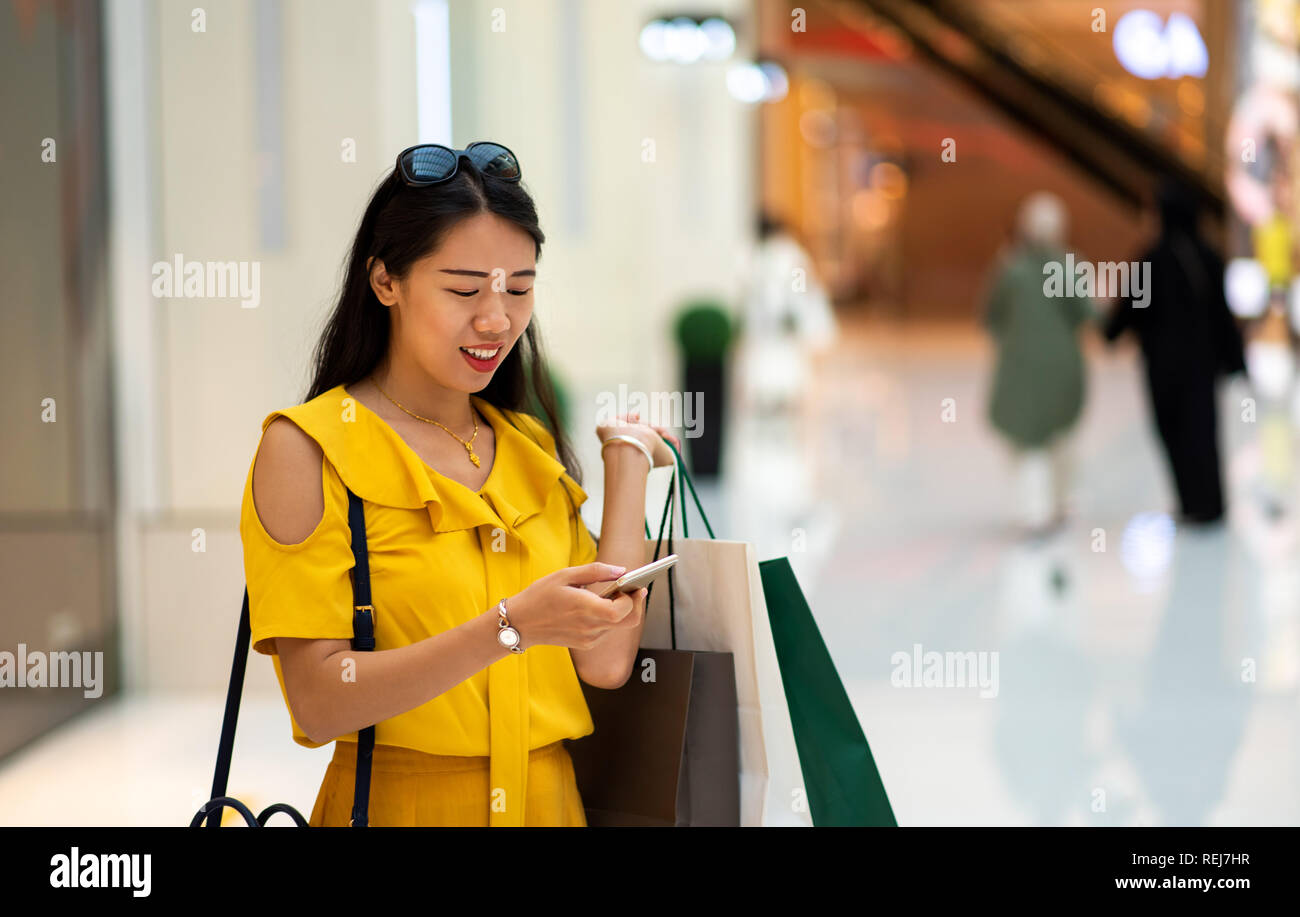 Asiatische Frau mit Phone in einem Einkaufszentrum Stockfoto